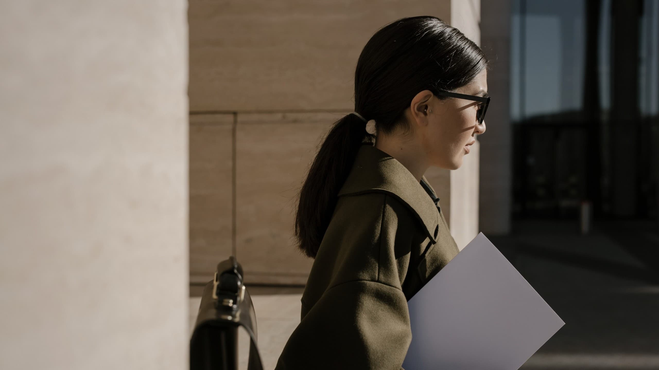 Professional carrying project documents through a modern civic building